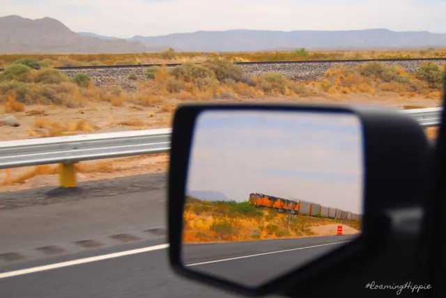 Dry plains and mountains reflected in a car's side mirror