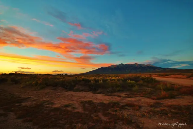 Pink and orange clouds over a wide, dry landscape