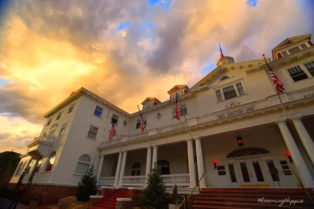 A large white historic hotel with flags under a golden evening sky