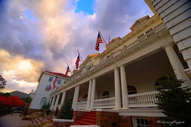 The long white porch of a historic hotel with flags