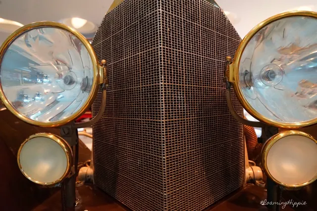 Brass headlamps and a tall grille on an antique car