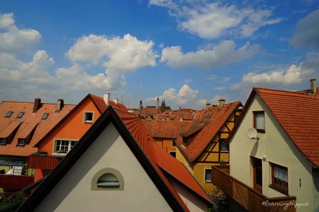 Red tiled rooftops of an old town under puffy clouds