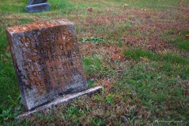 A tilted, lichen-covered headstone in the grass