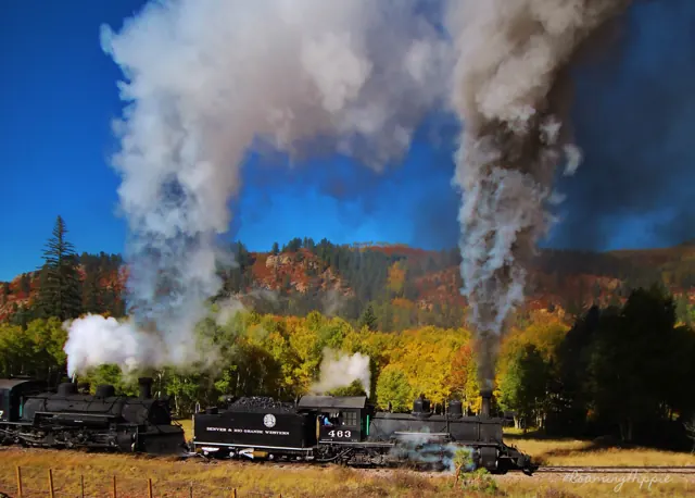 Two steam locomotives under billowing white smoke