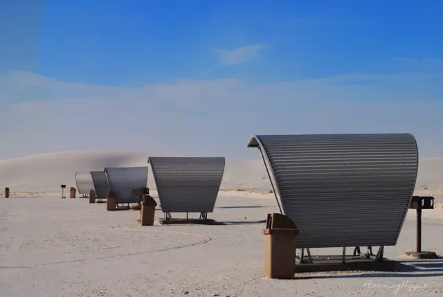 Rounded metal picnic shelters on bright white sand