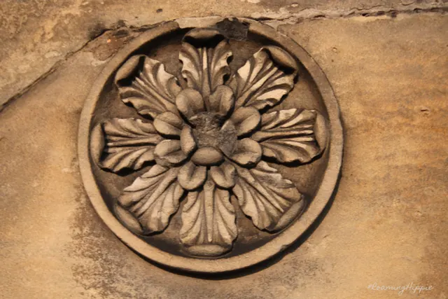 A carved stone flower set in a round frame
