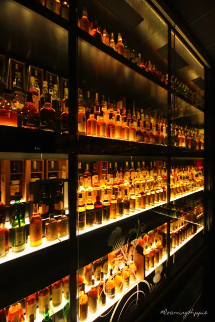 Glowing shelves of whisky bottles in a dark room
