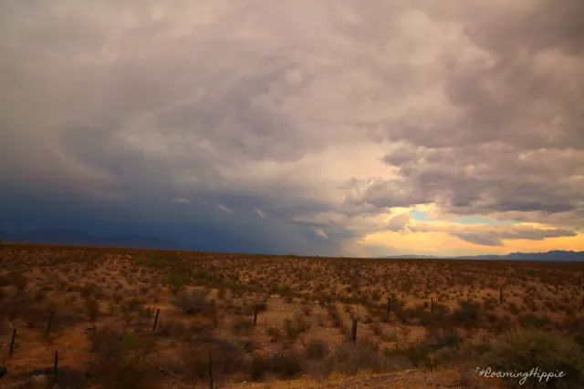 Storm clouds gathering over open desert scrubland at dusk