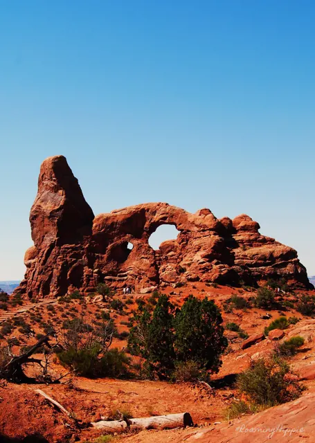 A red rock arch standing against a clear blue sky